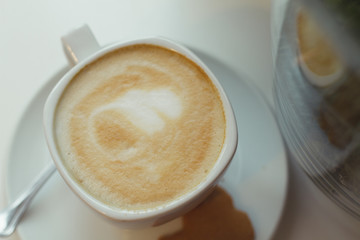Flat white coffee in a white cup and gingerbread cookies on the plate.