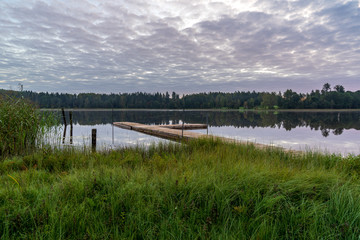 Obraz premium picnic area by the lake with wooden plank boardwalk