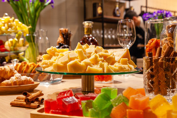 Closeup plate pieces Italian parmesan, flowers, bakery, marmalade, flowers, cinnamon at catering on cognac presentation. Concept birthday, whiskey degustation, brandy tasting