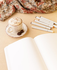 Open Sketch Book, bunch of artistic markers and Latte on a Table. Portrait layout