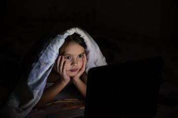 The girl under a blanket with a laptop.