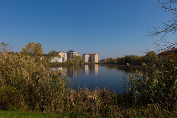 Fototapeta na wymiar Modern residential complex on the shores of a picturesque lake on a sunny day.