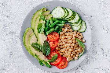 Healthy vegetarian food chickpeas, avocado, tomatoes, cucumbers, green beans top view
