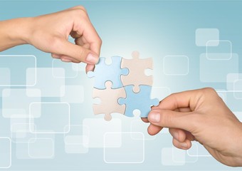 Human hands joining puzzle parts on background