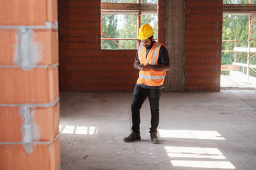 Man Working In Construction Site Smiling And Using Smartphone
