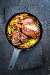 Traditional barbecue leg of lamb with lemon and tomatoes as top view in a cast-iron skillet