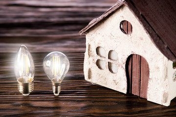 Led lamps lie near the house layout on a wooden background
