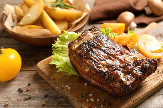 Delicious barbecued ribs served with garnish on wooden board