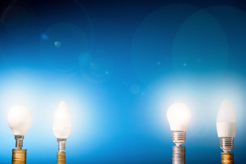 Led lamps stand on money coins on a blue background