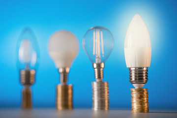 Led lamps stand on money coins on a blue background