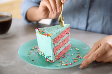 Woman eating fresh delicious birthday cake at table, closeup