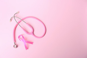 Obraz na płótnie Canvas Pink ribbon and stethoscope on color background, top view with space for text. Breast cancer concept