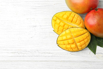 Flat lay composition with mango on white wooden background. Space for text