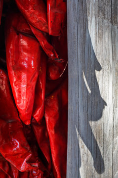 Bright red chile ristra with shadow cast on old wood