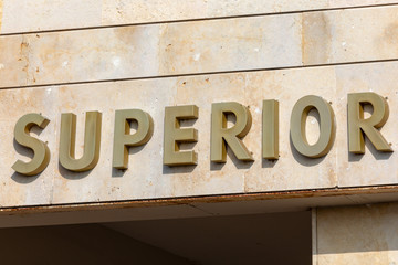 Poster with text "Superior" in Spanish. Label in metal letters.