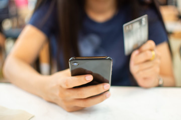 woman's hand holding smart phone and credit card for shopping online concept. Subject is blurred.
