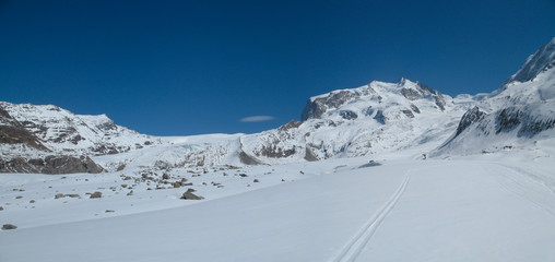 the Monte Rosa mountain range and Dufourspitze mountain peak in the Swiss Alps above Zermatt in winter with backcountry ski tracks in the foreground