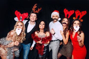 Six young funny friends, four girls and two boys while celebrating Christmas. Group of friends at...