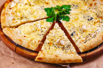Italian Pizza four cheese (quattro fromaggi) on wooden cutting board. Close up