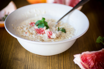 sweet oatmeal with slices of red grapefruit in a ceramic bowl