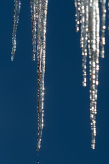 Hägende Eiszapfen vor blauem Himmel