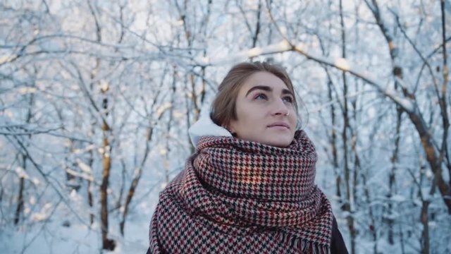 Portrait young woman standing looking up in the winter park smiling look around happy cold fun snow face forest happiness white sun nature season weather christmas vacation outdoor slow motion