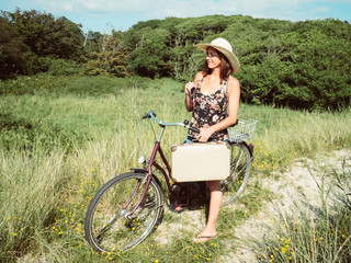 Obraz premium Vintage woman on a bike with a retro suitcase