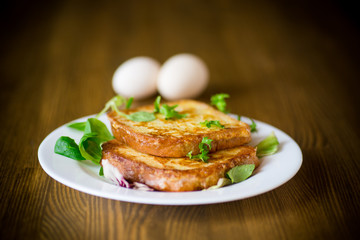 fried croutons in eggs with greens in a plate