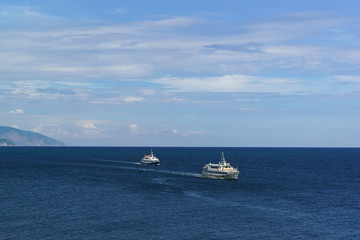 Two white ships sail the calm blue sea on a Sunny day