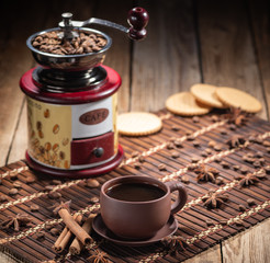 coffee beans in jute bag with coffee grinder and hot cup of coffee on wooden table