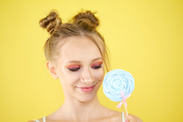 young girl with candy on a yellow bright background. beautiful make-up,