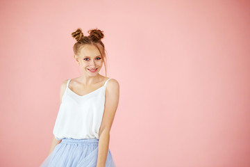 Close-up portrait smiling beautiful girl with funny hairstyle on a pink background. spring fashion...
