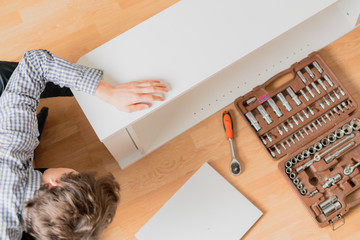 close up worker hand assembling the new furniture on the wooden floor in the new flat  h