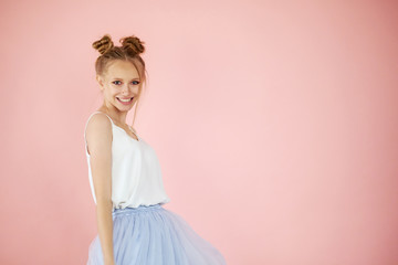 Close-up portrait smiling beautiful girl with funny hairstyle on a pink background. spring fashion...