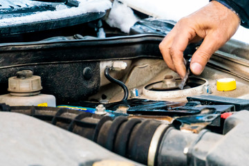 handyman changing antifreeze in broken car on a winter day f