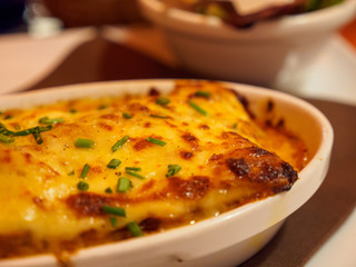 Closeup detail of a traditional lasagna bolognese in baking dish with bubbling cheese at an Italian restaurant. Shallow focus. Strasbourg, France. Travel and cuisine.