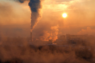 City factory with pipe releasing smoke at sunset in fog. Concept of ecocatastrophe.