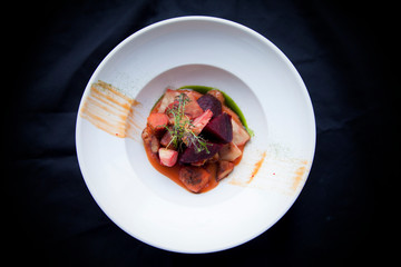 beet salad with vegetables in a white plate on a black background