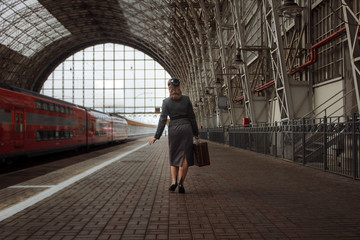 girl with a suitcase in hand and in retro clothes walking down the station