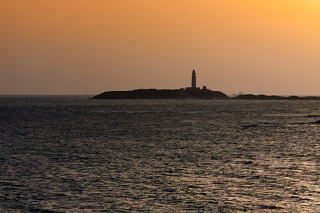 ATARDECER EN EL MAR CON FARO DE TRAFALGAR EN EL HORIZONTE