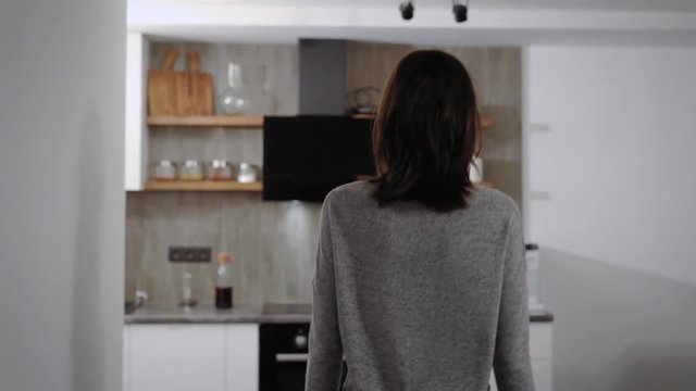 Young Woman Is Walking In Her Flat In Night Time, Moving On Kitchen And Taking Glass With Water