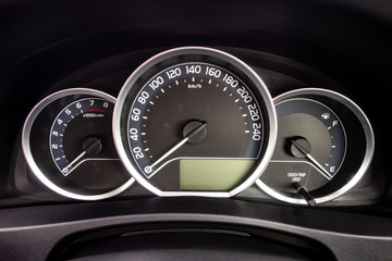 A detail of a dashboard of a modern car with odometer and other instruments