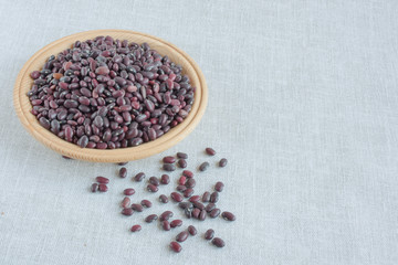 red beans on a wooden plate on a gray linen background
