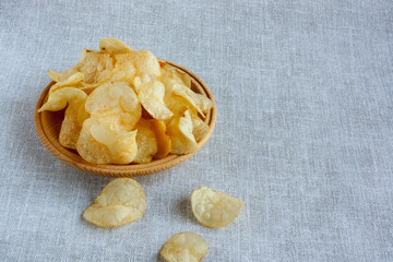 potato chips on a wooden plate on a grey linen background