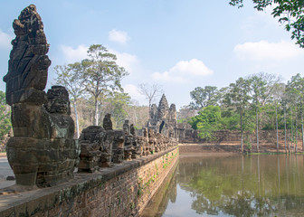 Fototapeta na wymiar Stone Asuras hold the nāga Vasuki on a bridge leading into the 12th century city of Angkor Thom.