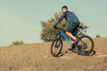 Cyclist in shorts and jersey on a modern carbon hardtail bike with an air suspension fork	