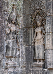 Fototapeta na wymiar Aspara ladies carved in the temple walls. The statues have weathered over time but remain beautiful and incredibly detailed