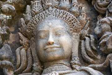 Fototapeta na wymiar he face of an Aspara lady carved in the temple walls. The statue has weathered over time but remain beautiful and incredibly detailed