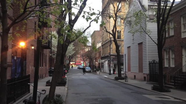 Camera tilts down to show establishing shot of a city street, trees, cars and apartment buildings in the West Village of Manhattan