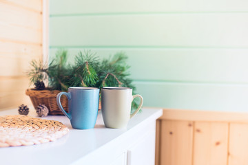 Morning interior. Two cups with a drink and a bouquet of pine needles on a white table in the morning Sunny day.